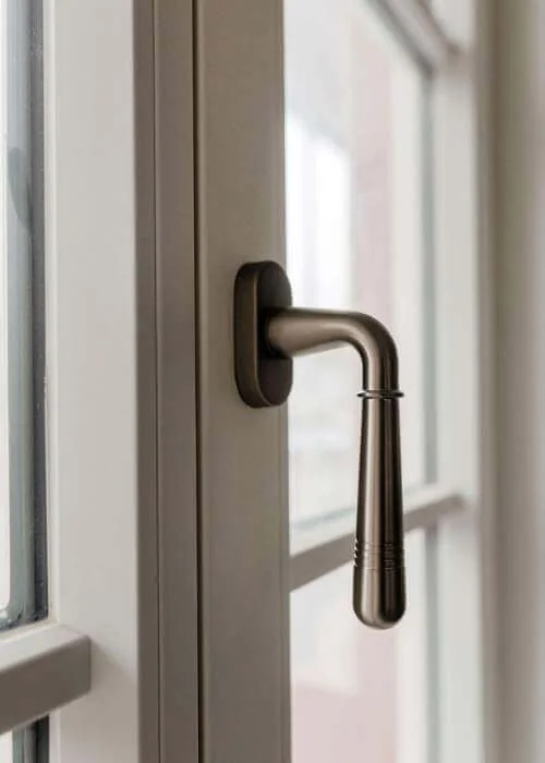 Dunkler Fenstergriff an einem weißen Fensterrahmen