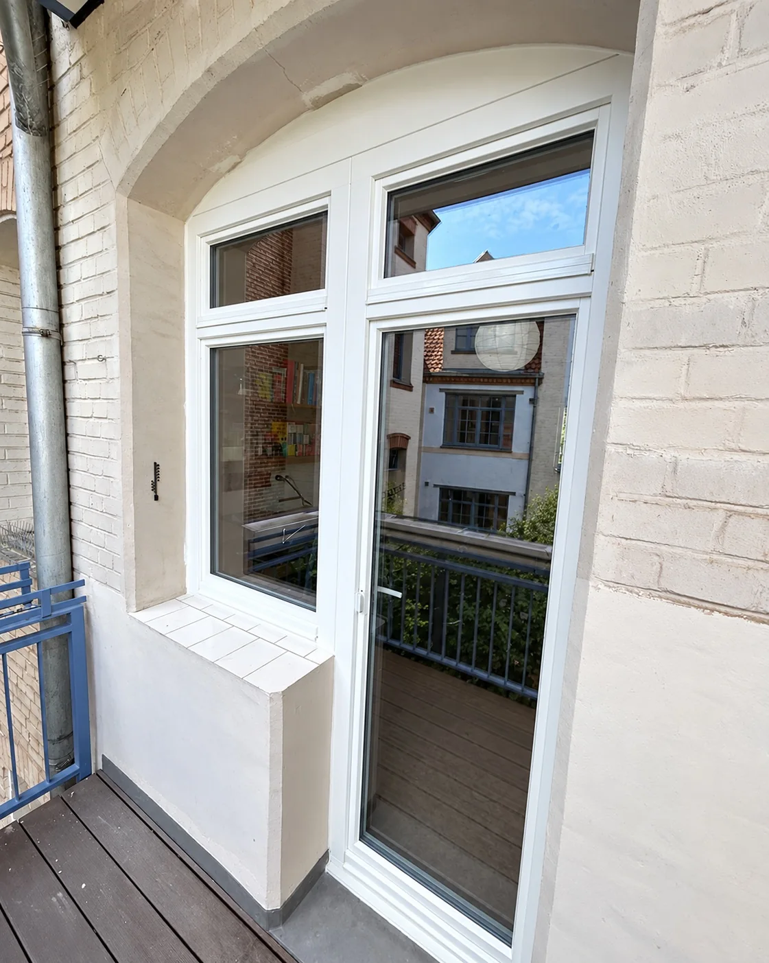 Weiße Balkon-Tür-Fenster-Kombination mit Oberlichtern in einer gemauerten Nische